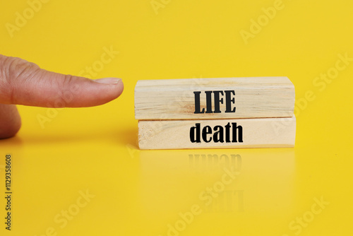 Life or Death symbol. Concept word Life or Death on wooden blocks. Businessman hand. Beautiful yellow background. Business and Life or Death concept. Copy space photo