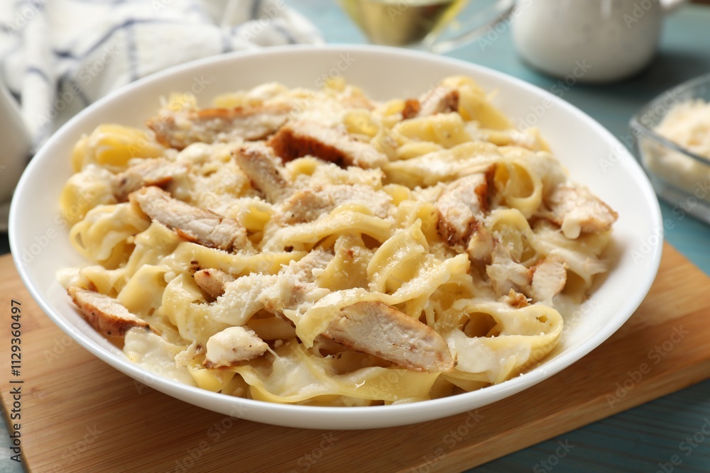 Tasty Alfredo pasta with chicken on light blue wooden table, closeup Tasty Alfredo pasta with chicken on light blue wooden table, closeup