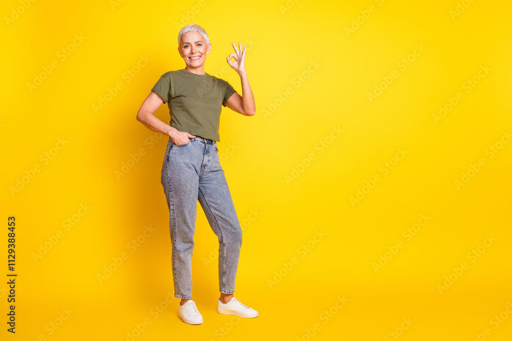 Full length photo of shiny attractive lady dressed khaki t-shirt showing okey empty space isolated yellow color background Full length photo of shiny attractive lady dressed khaki t-shirt showing okey empty space isolated yellow color background