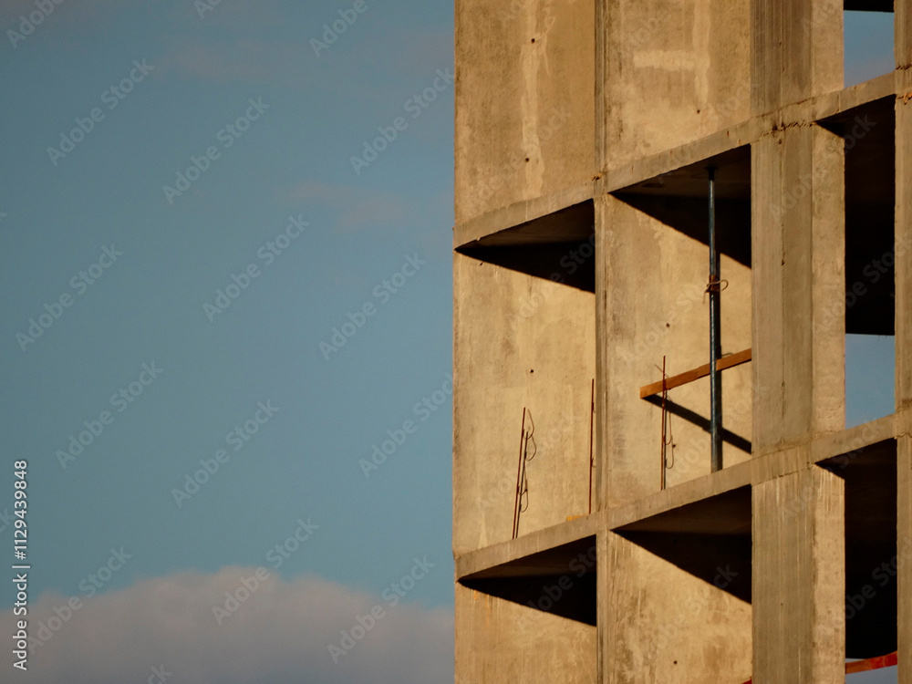 Close-up of a multi-story building under construction, focusing on its reinforced concrete framework Overcast day with diffused light Close-up of a multi-story building under construction, focusing on its reinforced concrete framework Overcast day with diffused light