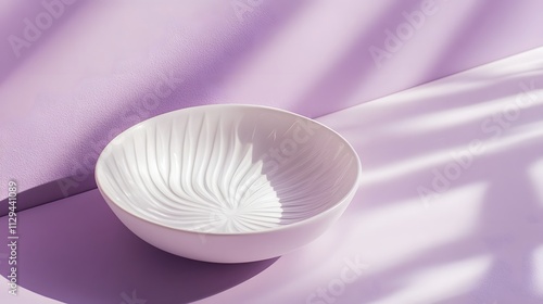 A white ceramic plate with subtle embossed details resting on a pastel purple background. photo