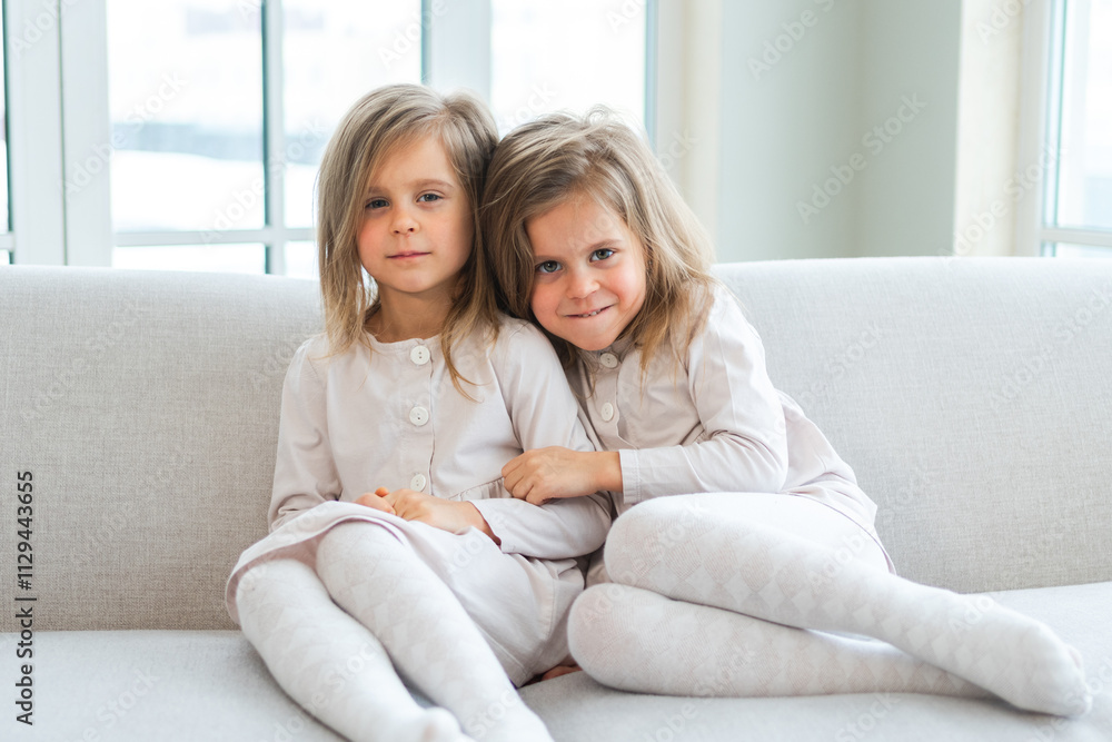 Happy family sisterly love. Two funny little twin sisters girls hugging with love care playing together at home indoors. Happy children lifestyle. Identical twin girls hugs. Girls friendship and youth Happy family sisterly love. Two funny little twin sisters girls hugging with love care playing together at home indoors. Happy children lifestyle. Identical twin girls hugs. Girls friendship and youth