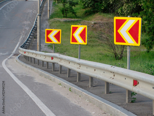 Image displays a road section with traffic merge signs, safety guardrail, and rural or suburban surroundings photo