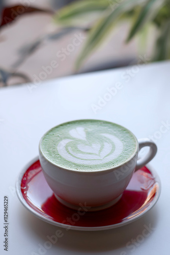 Ceramic Mug of Green Tea Matcha Latte Drink With Microfoam Art of Flower and Heart on White Cafe Table