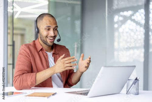 Photos Professional man in office participates in a virtual meeting using a headset and laptop