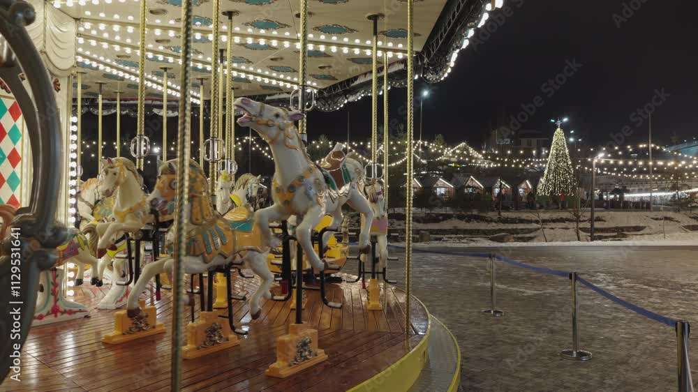 Illuminated Merry go round spinning.  Empty old fashion roundabout in park.