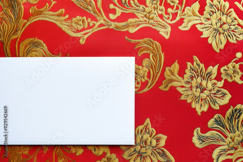 Blank white paper on red fabric with golden floral pattern background. Chinese New Year greeting card photo