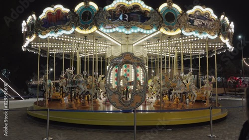 Illuminated Merry go round spinning.  Empty old fashion roundabout in park.