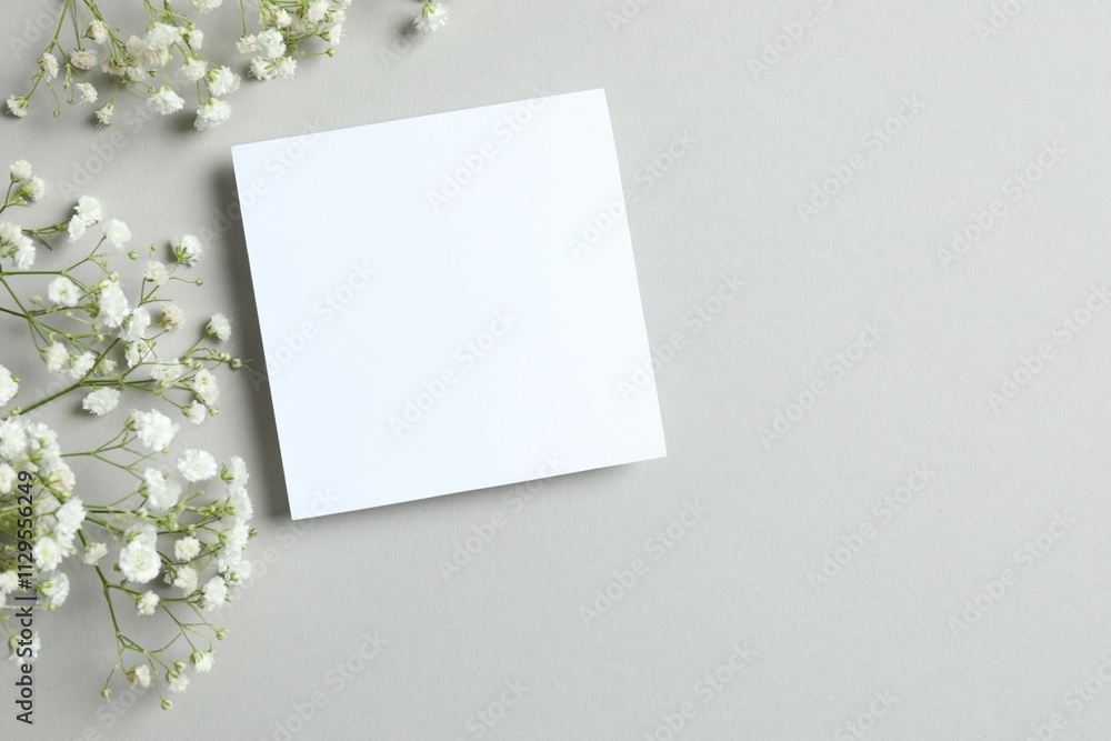 Top view photo with paper card and gypsophila flowers on gray background Top view photo with paper card and gypsophila flowers on gray background