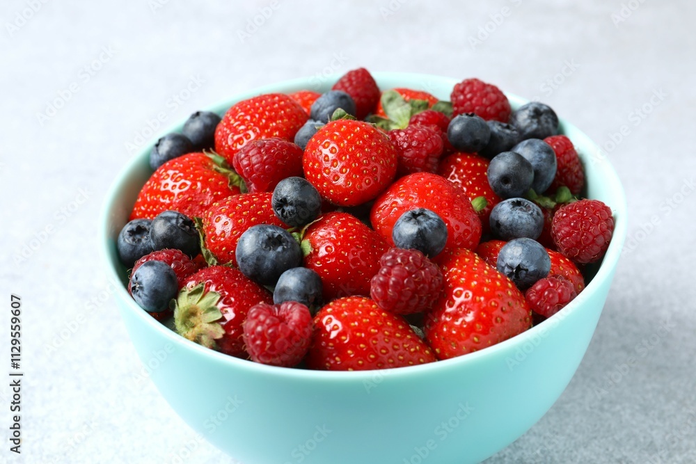 Different fresh ripe berries in bowl on wooden table Different fresh ripe berries in bowl on wooden table