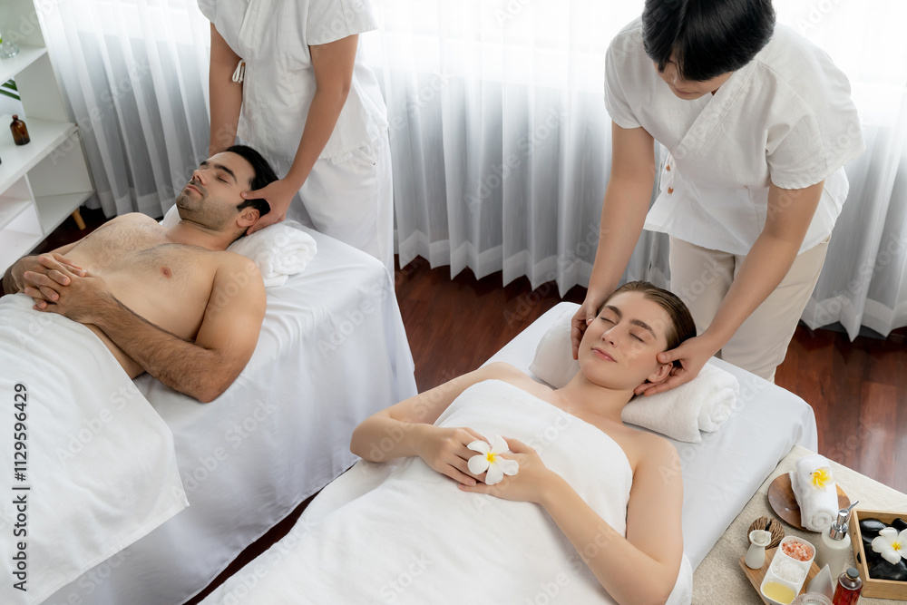 Caucasian couple enjoying relaxing anti-stress head massage and pampering facial beauty skin recreation leisure in dayspa modern light ambient at luxury resort or hotel spa salon. Quiescent Caucasian couple enjoying relaxing anti-stress head massage and pampering facial beauty skin recreation leisure in dayspa modern light ambient at luxury resort or hotel spa salon. Quiescent
