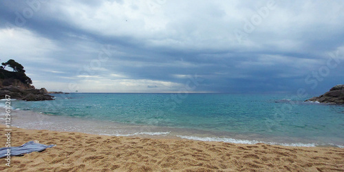 Sandy beach shore. Calm sea after rain. Seascape with dramatic sky.