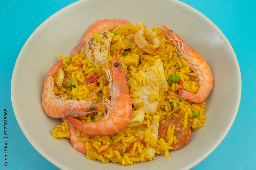 assiette de paella, vue du dessus, en gros plan,, isolée sur un fond bleu assiette de paella, vue du dessus, en gros plan,, isolée sur un fond bleu