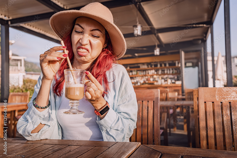 Tourist making a disgusted face while drinking a bad coffee in an outdoor cafe