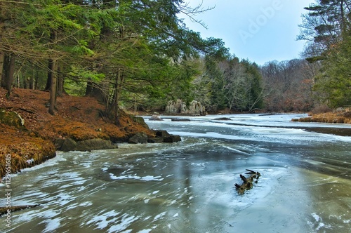 Beautiful wilderness landscape of the partially frozen Eau Claire River passing through a forest on a winter day near Aniwa, Wisconsin.