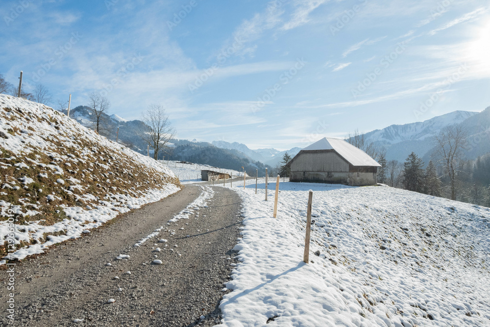 Rural road going past a big swiss traditional house in the high alps of Switzerland Rural road going past a big swiss traditional house in the high alps of Switzerland