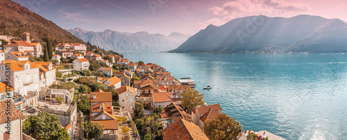 Obraz na płótnie Orange rooftops of Perast village blend with the tranquil blue waters of the bay of Kotor, nestled amidst Montenegro breathtaking mountains at sunset w salonie