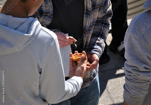 Group of people on the street eating a typical Portuguese sweet called nata com canela