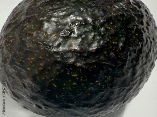 Closeup dark green avocado with volcano crater shaped surface defect on white background  photo