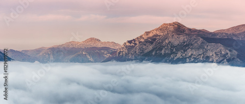 Obraz na płótnie Stunning panoramic view of mountain peaks rising above a thick layer of clouds during a vibrant sunset, creating a breathtaking natural spectacle w salonie