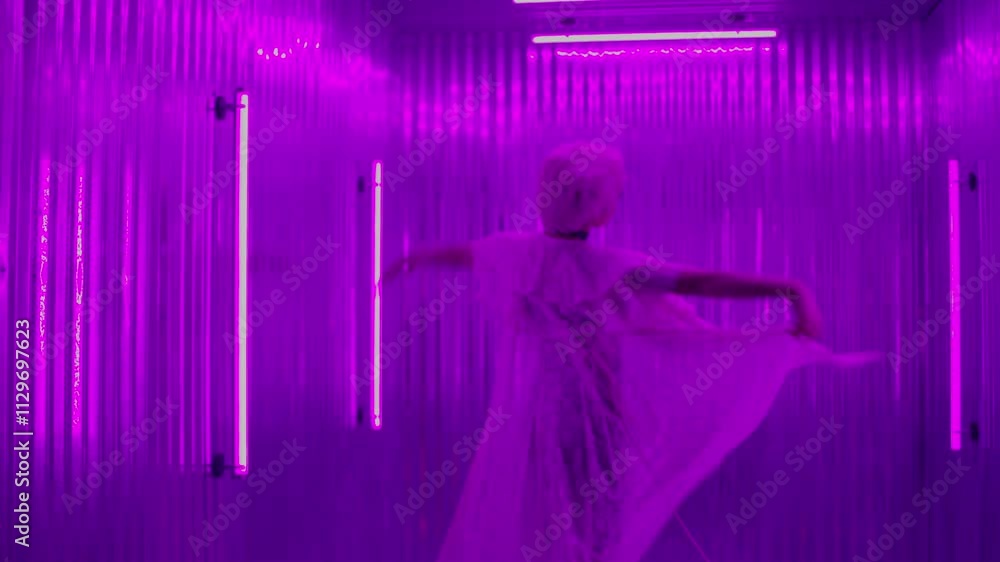 Woman dances in a metal walled room with colorful lights during a music video Woman dances in a metal walled room with colorful lights during a music video