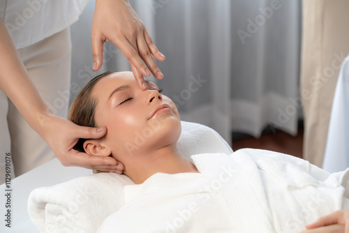 Caucasian woman enjoying relaxing anti-stress head massage and pampering facial beauty skin recreation leisure in dayspa modern light ambient at luxury resort or hotel spa salon. Quiescent