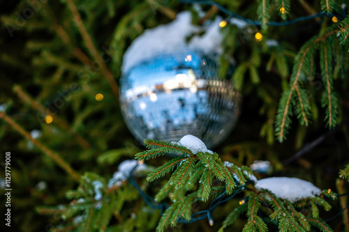 Christmas disco ball decoration on a snowy Christmas tree branch. Selective focus photo