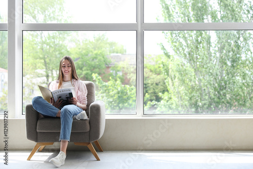Free Download Young woman reading magazine while sitting in armchair near large window in room - GFXLoad