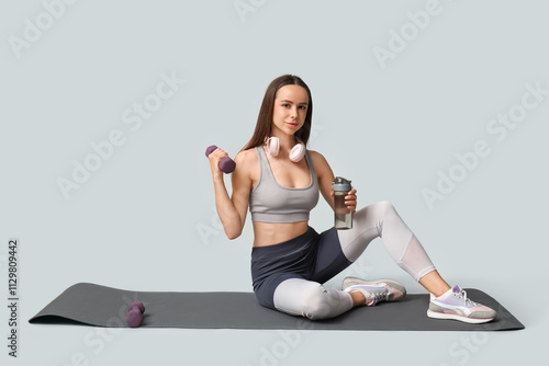 Wallpaper Mural Young female trainer with headphones, dumbbells and bottle of water on white background Torontodigital.ca