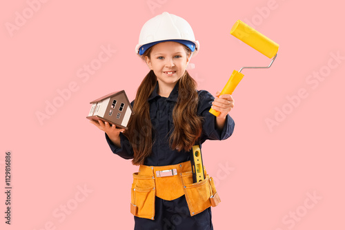Cute little architect with house model and paint roller on pink background