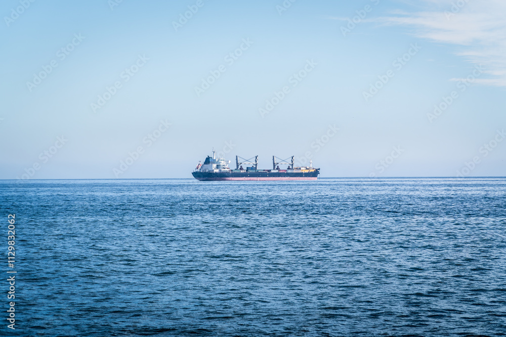 A large container cargo ship travels over calm, blue ocean A large container cargo ship travels over calm, blue ocean