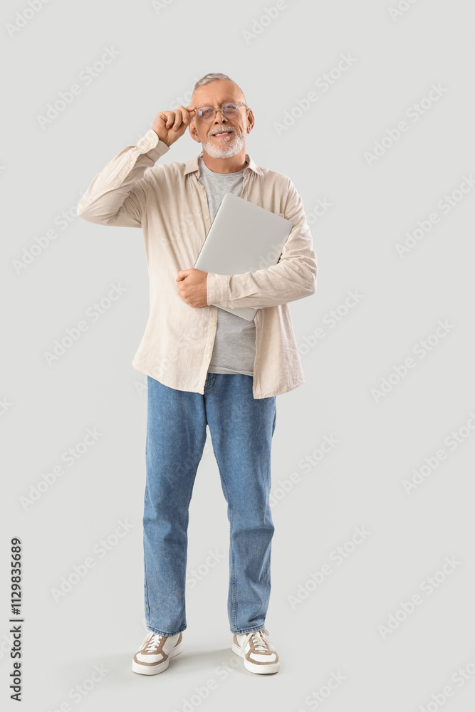 Mature programmer with laptop on light background Mature programmer with laptop on light background