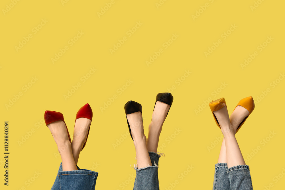 Female legs in stylish high-heeled shoes on yellow background Female legs in stylish high-heeled shoes on yellow background