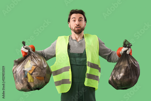 Shocked male scavenger with full garbage bags on green background