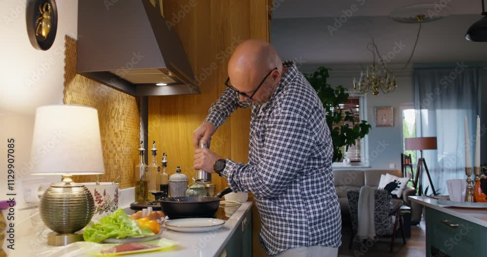 A man cooks breakfast at home, he adds spices to the pan. A man cooks breakfast at home, he adds spices to the pan.
