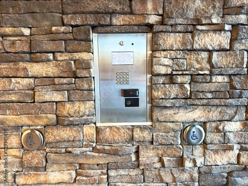 metal intercom panel mounted on a stone wall