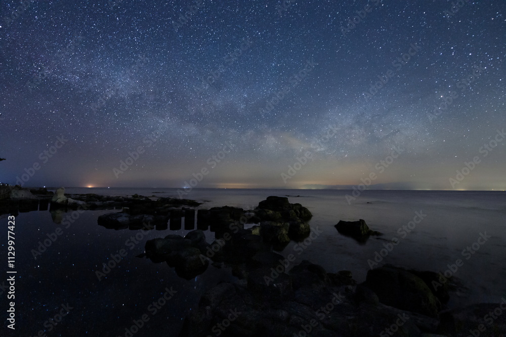 海岸の水面に輝く星々と能登半島の星空