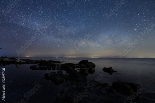Obraz na płótnie 海岸の水面に輝く星々と能登半島の星空 w salonie