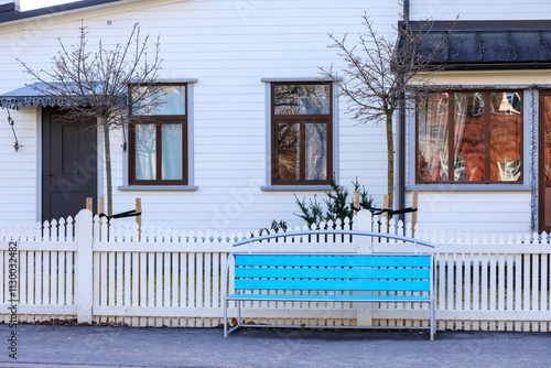 A blue wooden bench in front of a white house