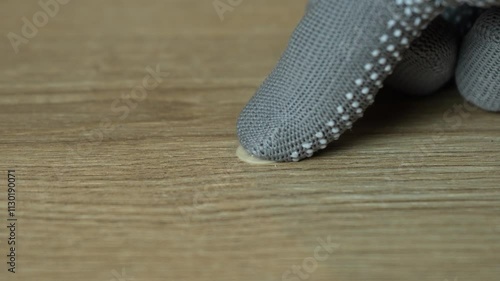 A man's hand glues a plug to a confirmat on a wooden board. Carpenter's hands in work gloves close-up. Slow motion. High quality FullHD footage photo