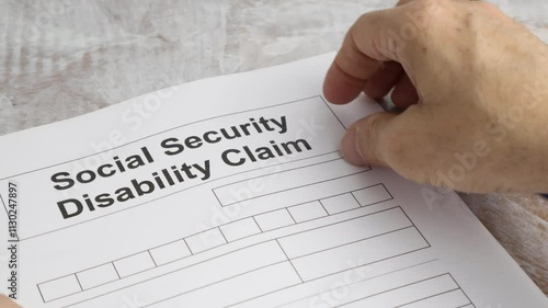 Social Security Disability Claim Man's hand moves sheet to foreground. photo