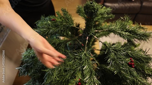 close-up shot of a woman building an artificial Christmas tree in a living room photo