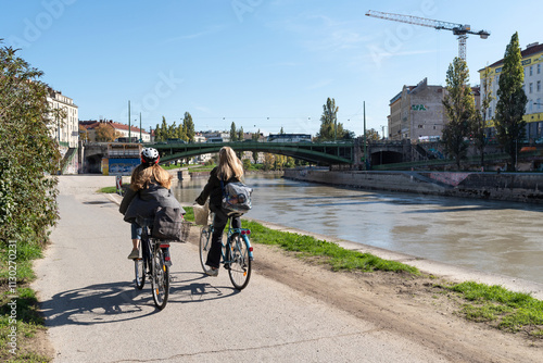 Two women cycling through the Donaukanal in Vienna, Austria