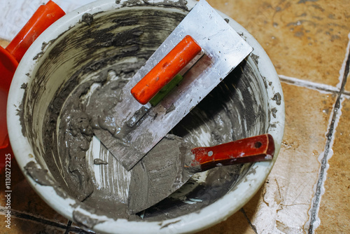 Obraz na płótnie Two construction spatulas on a bucket of glue. w salonie