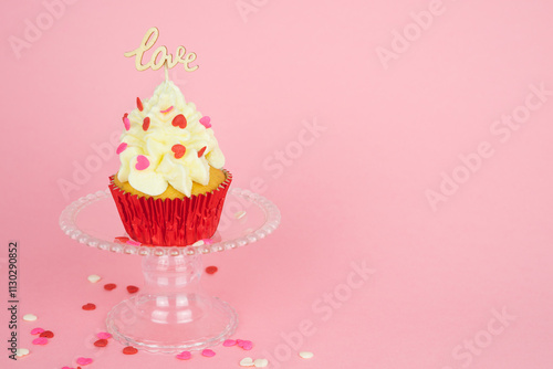 Valentine's Day. A cupcake with cream and red topping decoration with a wooden sign with the word LOVE on a pink background. Pastry bakery.