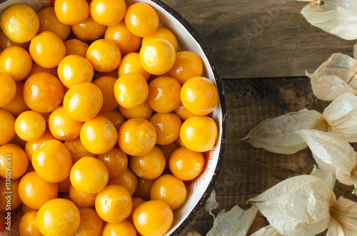 a bowl with golden berries and dried leaves. Physalis peruviana