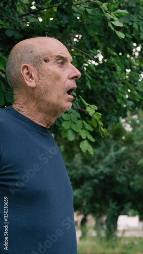 Scared Elderly Bald Man Looks Terrified In Shock Sitting Under A Tree photo