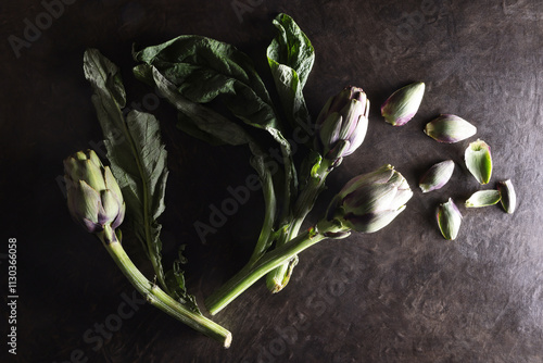 Natura morta, composizione con carciofi, isolati su fondo materico marrone scuro photo