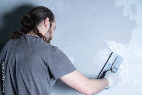 A professional plasterer applies a layer of decorative plaster to the wall. The concept of renovation and repair. Front view