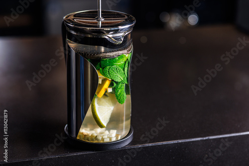 vitamin tonic tea with lemon, ginger and mint, on a dark background in a transparent teapot